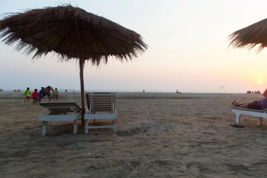 a beach with a straw umbrella and chairs